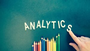 pexels-photo-185576-185576 Colored pencils and letters spelling 'ANALYTICS' on a textured background with a hand.